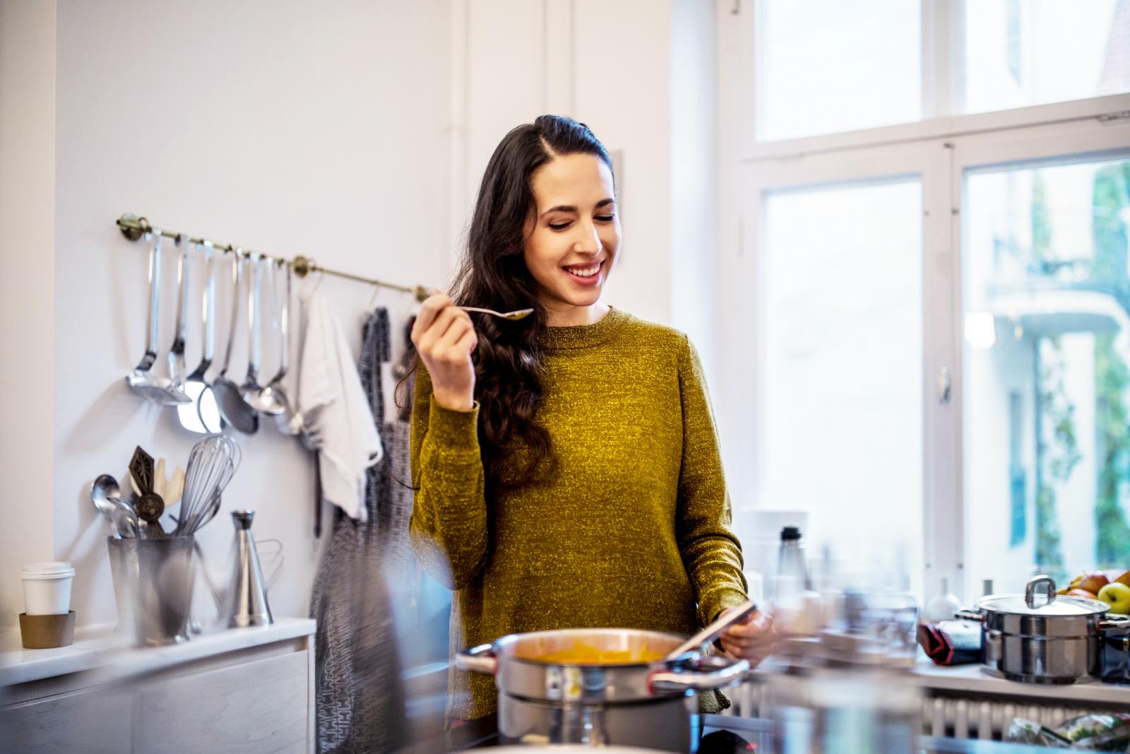 Woman tasting soup in kitchen