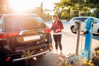 Woman charging electric car at station