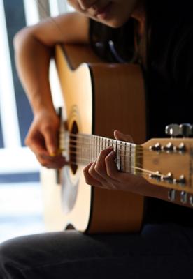 A lone guitarist fingers a chord.