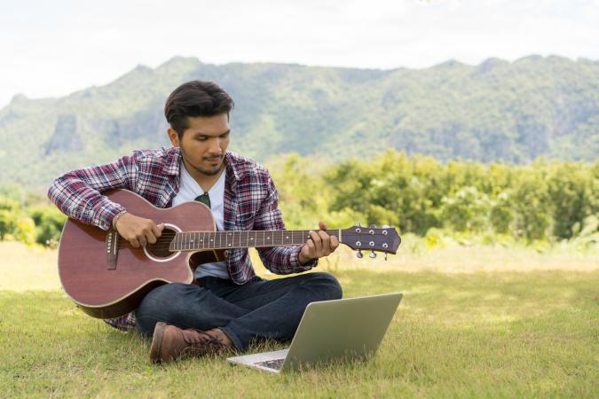 playing guitar while looking at laptop