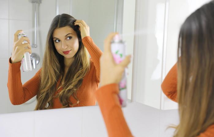 Woman Spraying Product On Hair