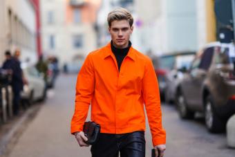 Man in orange jacket with black clutch purse