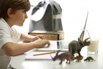 Kid doing his homework surrounded by dinosaurs