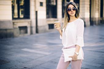 Young businesswoman carrying a white handbag and coffee