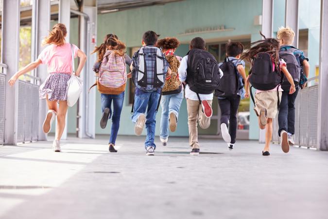 children with backpacks running