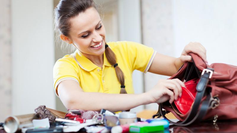 Young woman looking for something in cluttered handbag