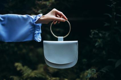A woman's hand holds handbag in her hand