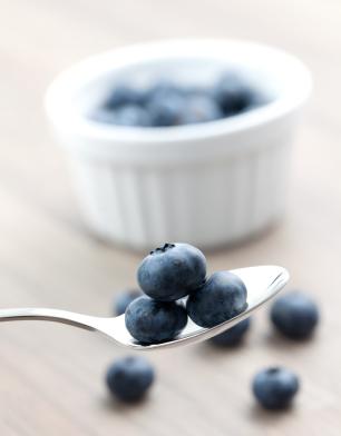 A Spoonful of Bilberries with Bowl in Background