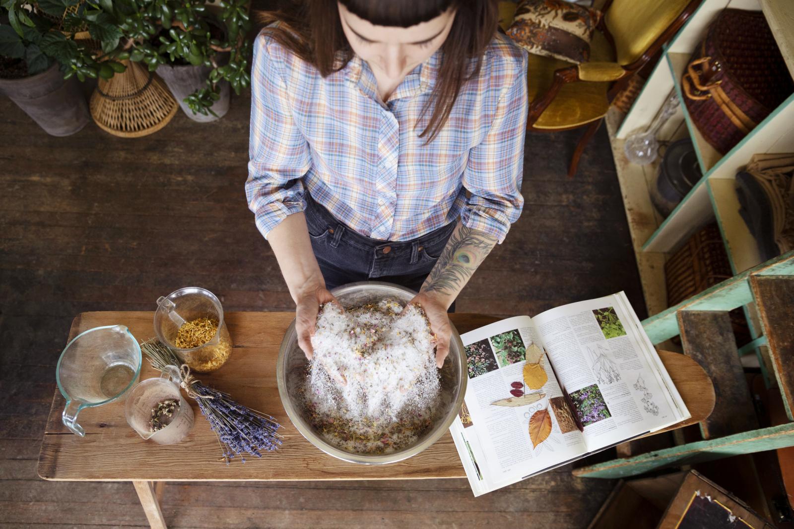 Female business owner mixing herbs and dried flowers in apothecary shop