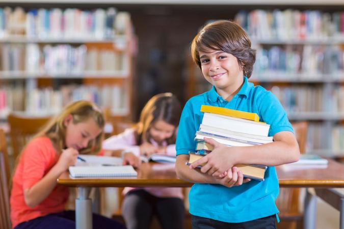 Boy carrying pile of library books