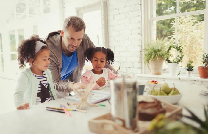 father and daughters coloring in kitchen