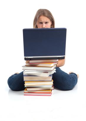 Girl behind computer with textbooks