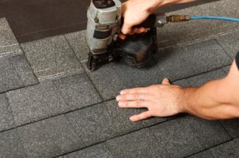 Two people shingling a roof