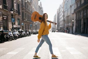 Red-haired woman with a guitar on zebra crossing
