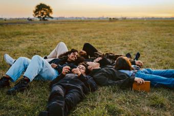 friends laying in grass together looking at sky