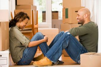 Capricorn woman having fun with spouse taking break with moving boxes