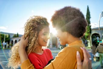 Two young women embracing, smiling, enjoying autumn beauty in