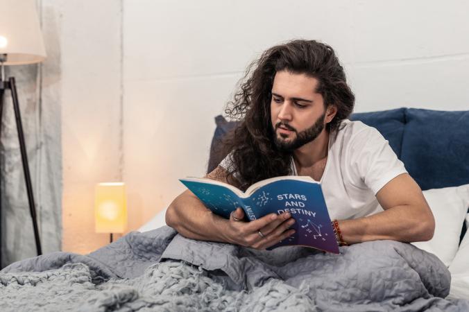 Man reading horoscope in bed