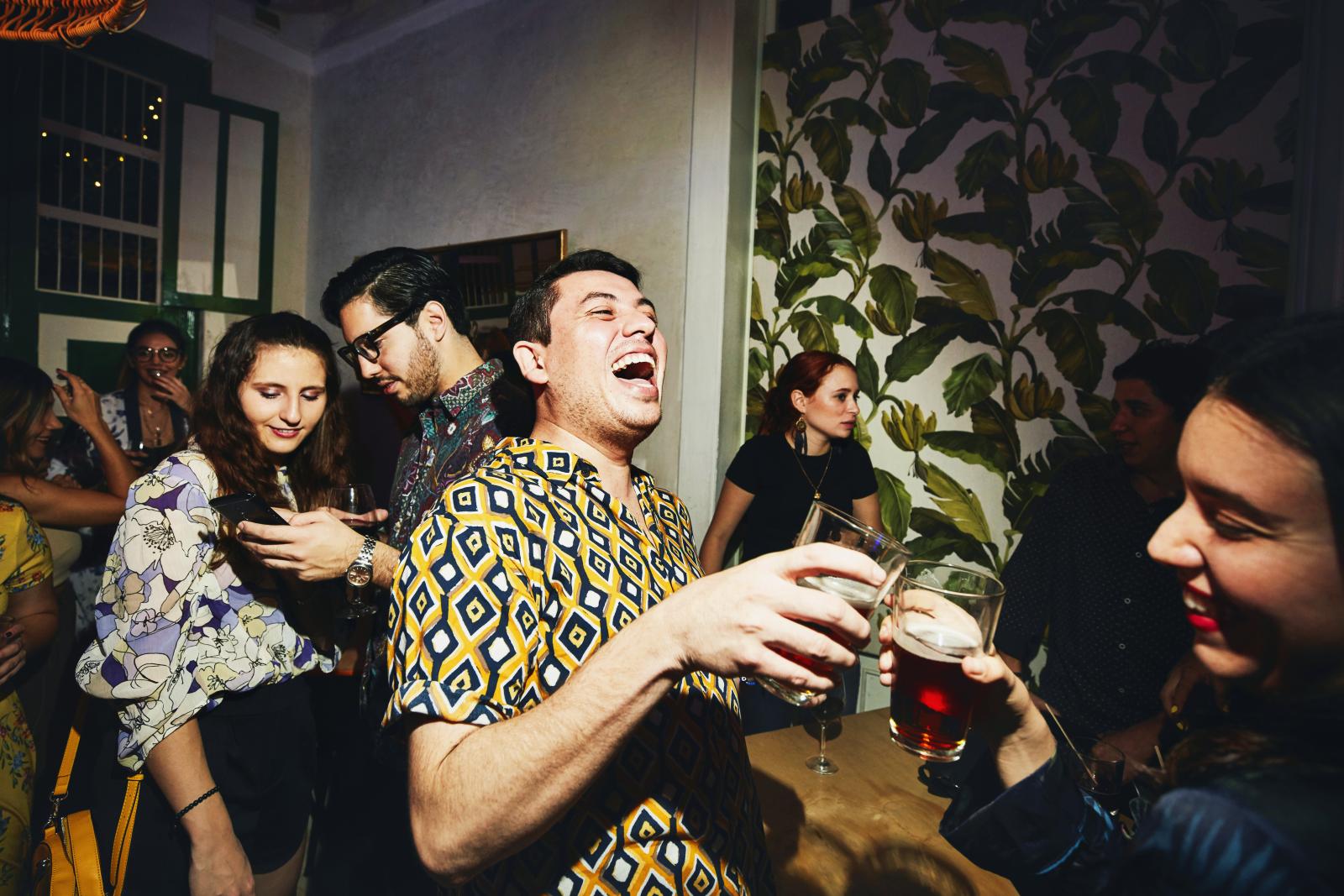 Laughing friends toasting during party in night club