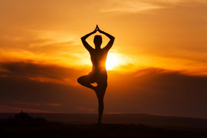 Silhouette of woman doing yoga at sunset