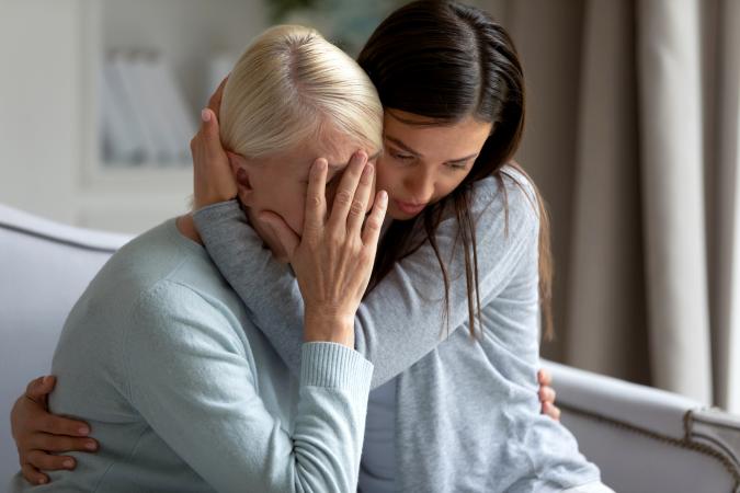Empathic young lady embracing and soothing elder lady