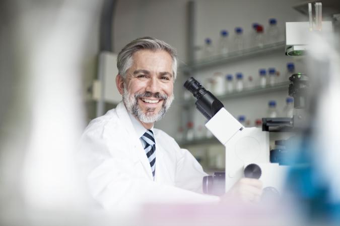 Smiling scientist in laboratory with microscope