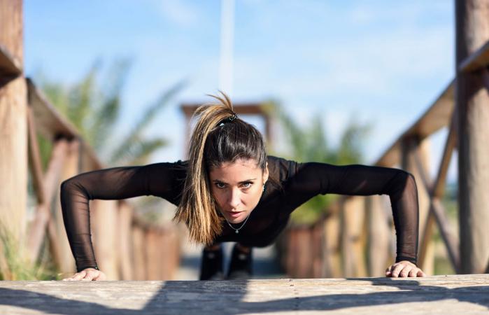 woman doing push-ups on wooden bridge