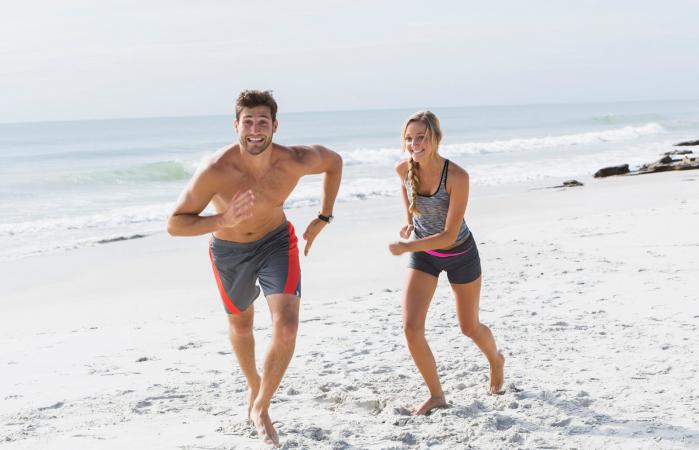 Pareja joven corriendo en la playa