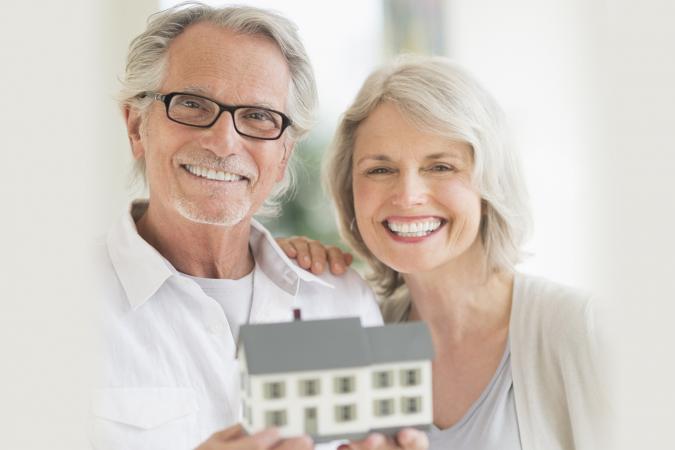 Senior couple holding model house