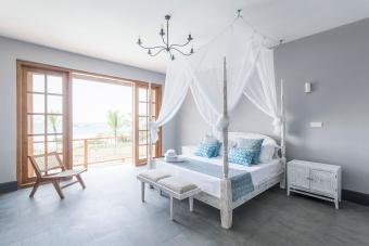 Four poster bed with mosquito net in bright hotel room