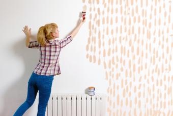 Young woman painting wall with brush