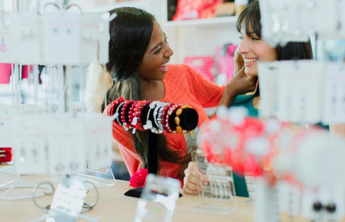 Women trying on jewelry together in clothing store