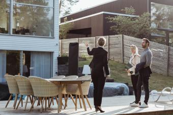 agent showing new property to couple outdoors