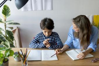 Tutor explaining to boy through book on table at home