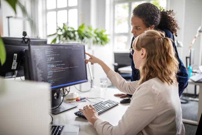 Two women coworkers working with computer programming