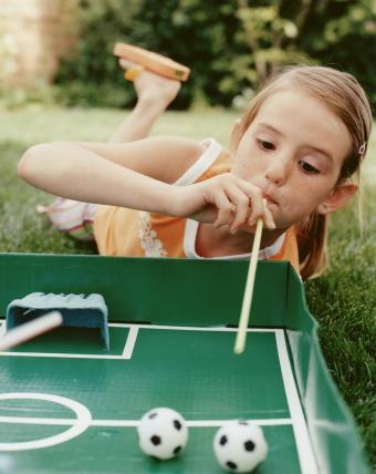 Girl blowing at soccer ball using straw