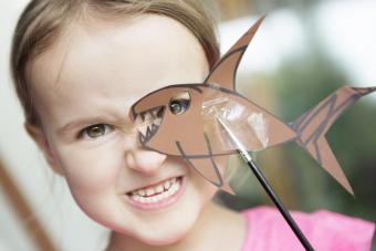 Child looking through a fish shaped paper cut out