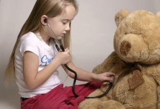 Girl examining a Teddy bear with a stethoscope