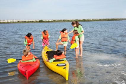 camp counselor with kids and kayaks