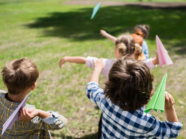 Young children throwing paper planes outdoors