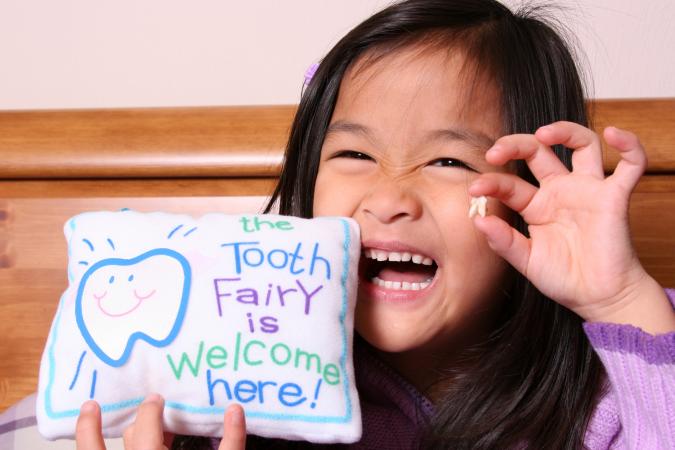 little girl holding up her tooth