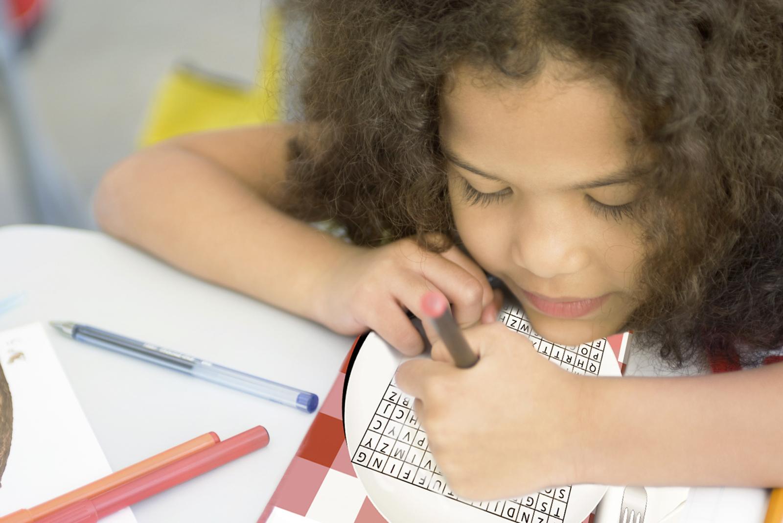 Little girl solving word search puzzles