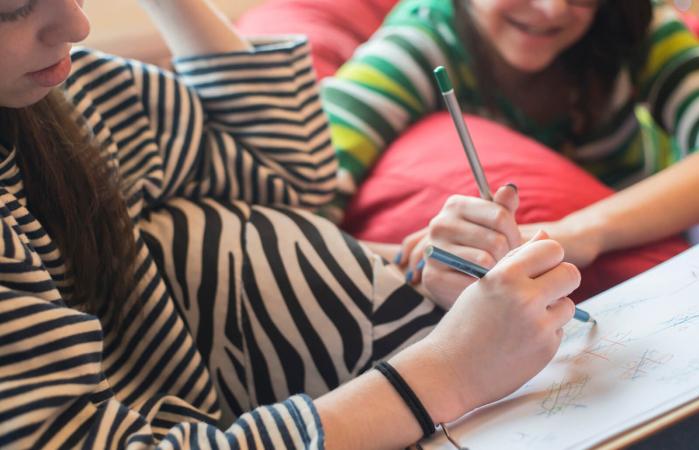 Two teenager girls play tic tac toe