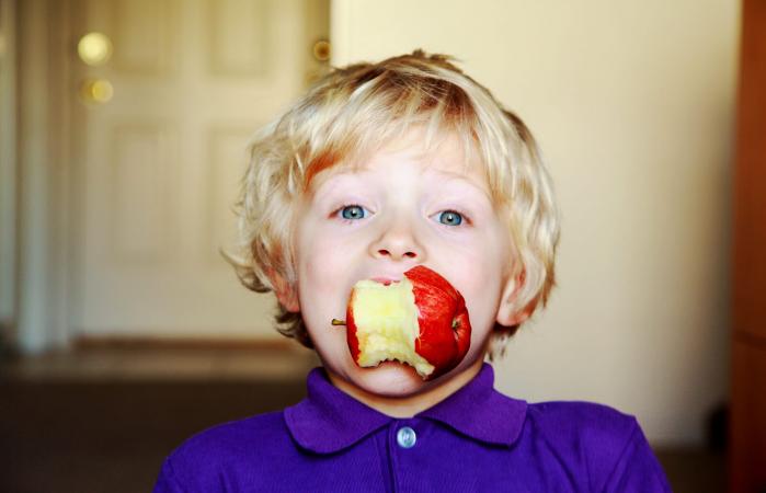 Boy eating a red apple