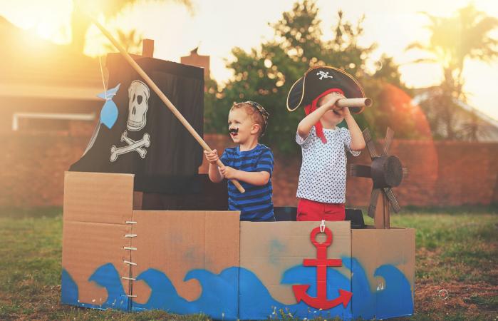 Boys playing pirates in a cardboard ship