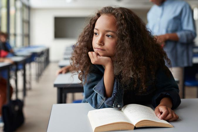 girl in class with book thinking