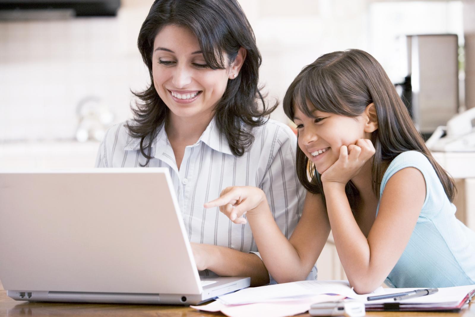 Woman and young girl in kitchen with laptop