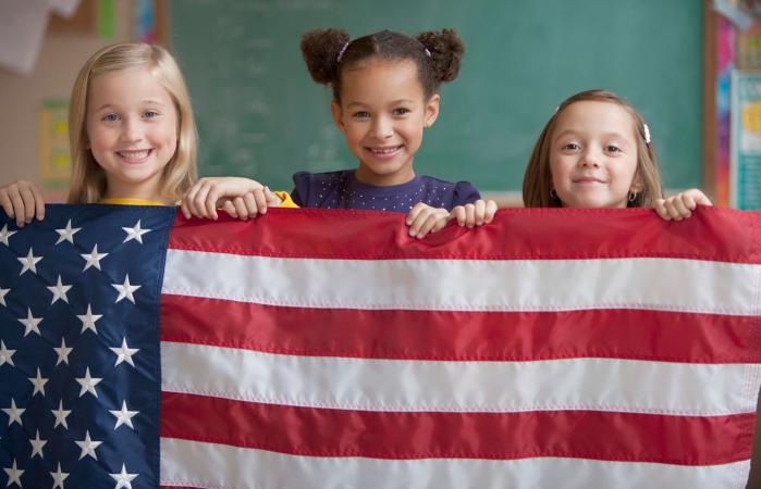 Students in classroom holding American flag