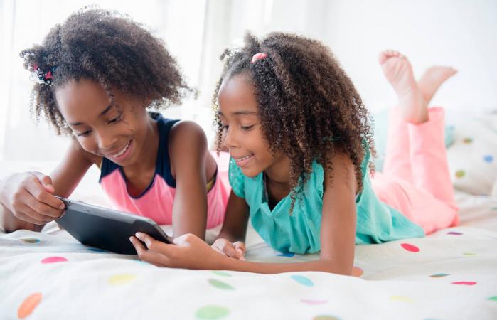 sisters using digital tablet on bed