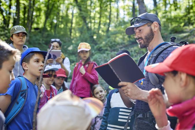 Man reading to kids on a field trip in forest
